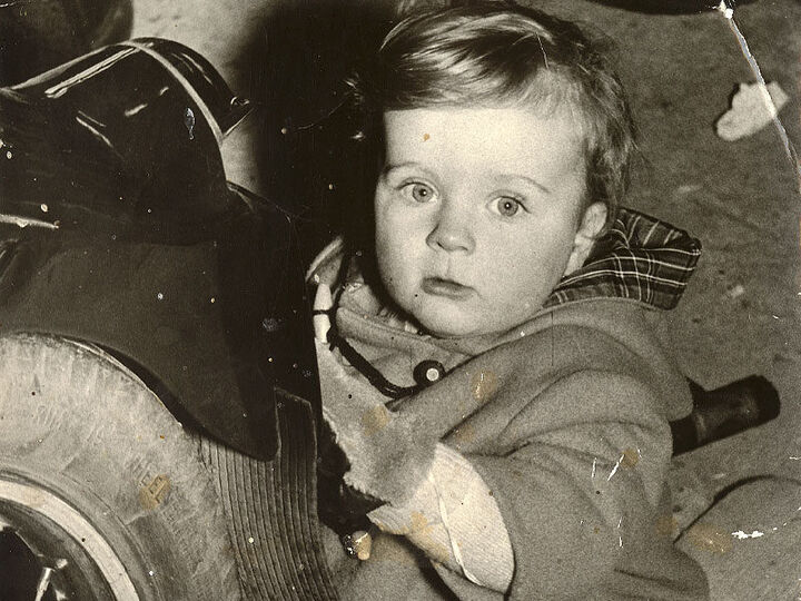 Stephen at 16 months, cleaning number plate, 1957.